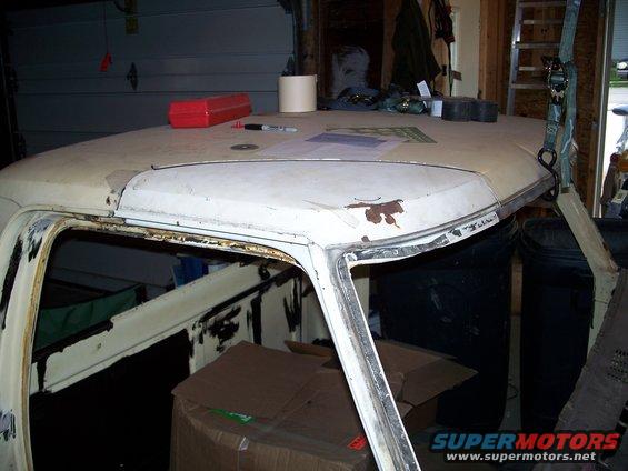 White 1979 Ford F-150 cab roof with rust spots, viewed from a 3/4 front angle inside a garage