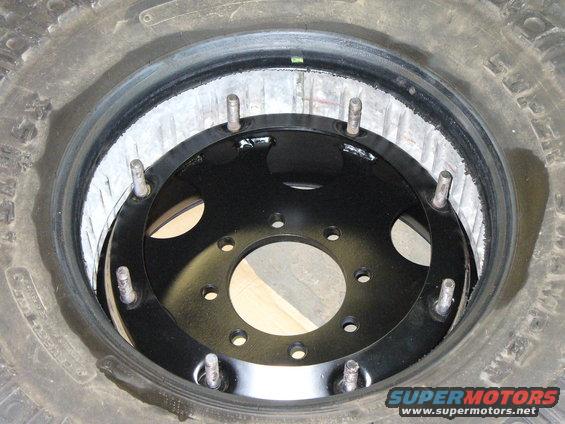 Spare tire showing a black wheel adapter with multiple bolt holes inside the rim