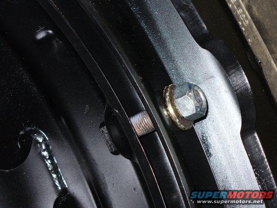 Close-up of a silver lug nut and washer on black metal