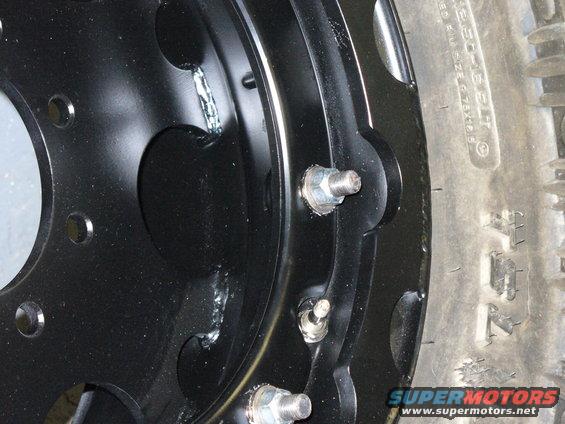 close-up of a black steel wheel with lug nuts and a tire sidewall visible