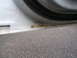 2000 Ford Crown Victoria - Rust is visible on the lower edge of a white car door sill, with asphalt below.