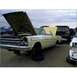1973 Ford Ranchero - A yellow convertible sits in a junkyard with its hood open, surrounded by other vehicles under a cloudy sky.