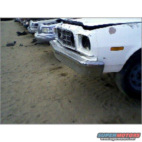 row of old cars parked on dirt lot, front ends visible