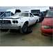 1973 Ford Ranchero - A white 1972 Ford Ranchero sits in a junkyard with its hood open and a missing front tire.