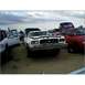 1973 Ford Ranchero - A white 1973 Ford Ranchero sits in a junkyard with other vehicles.