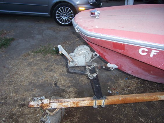 Boat on trailer with winch, car parked nearby