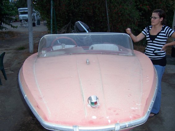 Pink boat with chrome trim and a woman standing next to it
