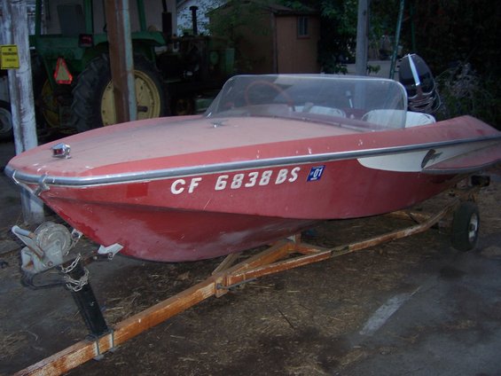 red boat with white trim and windshield on a trailer, license plate CF 6838 BS