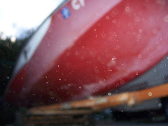 Red boat hull with white stripe, seen from a low angle, resting on a trailer