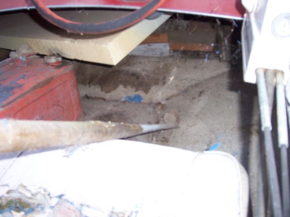 Boat interior showing a red gas can, white seat cushion, and some pipes