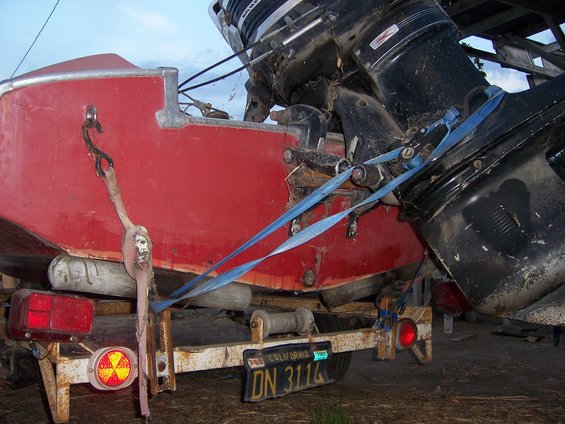 red boat on trailer with two black outboard motors, straps holding it down, California license plate DN 3114