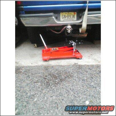 Blue pickup truck rear bumper, New Jersey license plate GN-893K, skull hitch cover, and a red floor jack