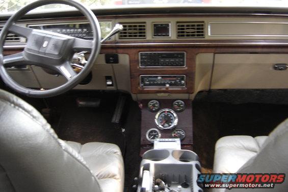 Interior shot of a car's dashboard, steering wheel, and center console with aftermarket gauges