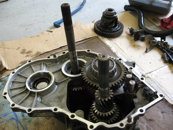 Transmission gears and differential inside an open casing, with tools on cardboard