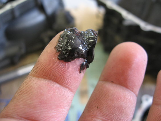 Black sludge on a finger, possibly engine oil or grease