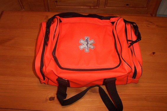 Orange medical bag with black trim and straps. Has a silver Star of Life emblem on the front