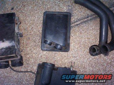 Ford Bronco air filter housing and hoses on concrete floor. SuperMotors logo visible