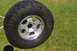 1986 Ford Bronco - A single off-road tire and rim rests on a grassy lawn, possibly after being cleaned.