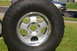 1986 Ford Bronco - A close-up of a tire and wheel assembly is shown with a silver SUV in the background.