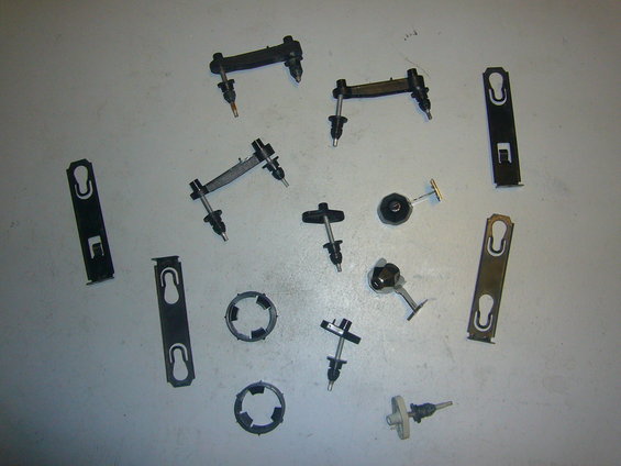 Assortment of black and metal automotive clips and fasteners laid out on a gray surface