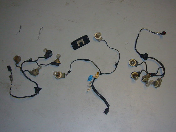 Wiring harnesses with several light bulbs and a black plastic mounting bracket laid out on a gray surface