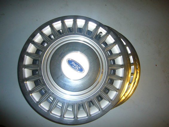 Stack of four Ford hubcaps with the Ford logo in the center
