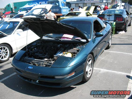 Dark teal 1995 Ford Probe with hood open, parked at a car show next to other vehicles