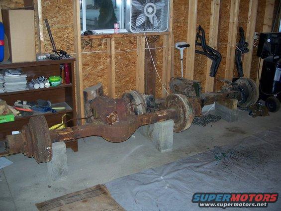 two rusty truck axles on concrete blocks in a garage
