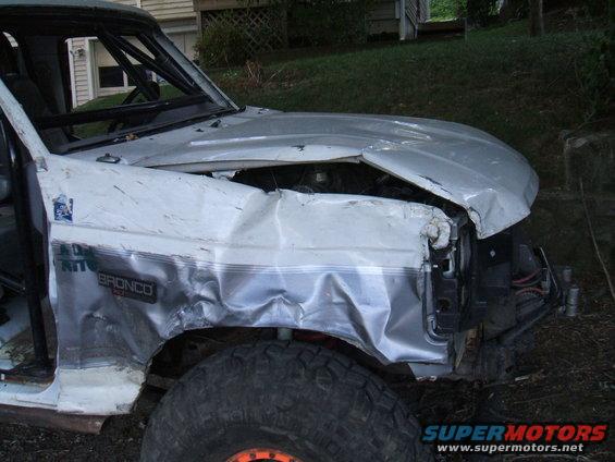 Front fender and hood of a white 1995 Ford Bronco showing significant collision damage