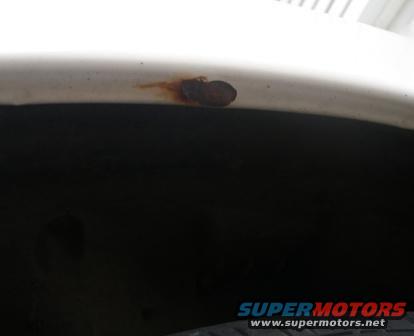 White wheel well with a rust spot on the fender lip