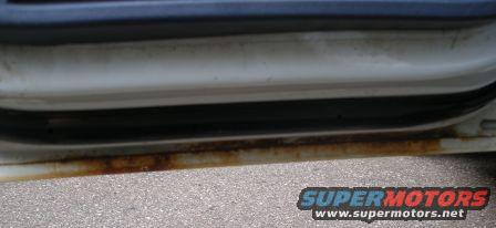 Close-up of a rusted door sill on a white vehicle
