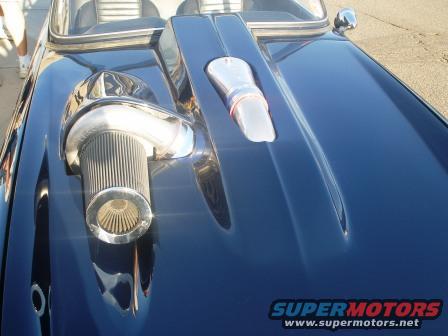 Dark blue car hood with chrome turbocharger and air filter, plus a chrome scoop