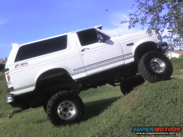 White lifted SUV with FX4 decal on rear quarter panel, driving up a grassy incline