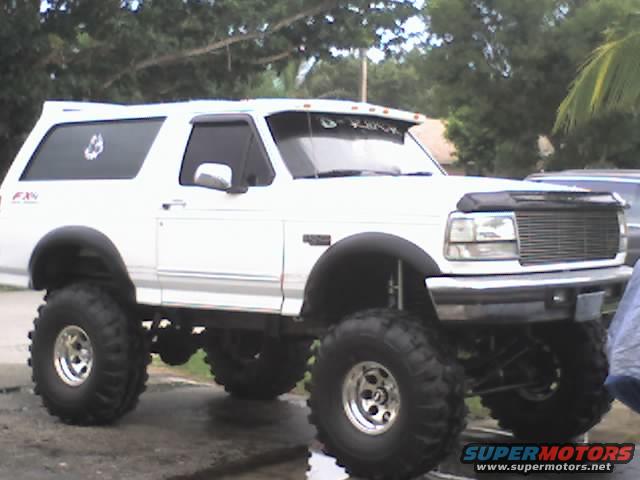White lifted 1992 Ford Bronco with oversized tires and aftermarket grille, viewed from the front three-quarter angle