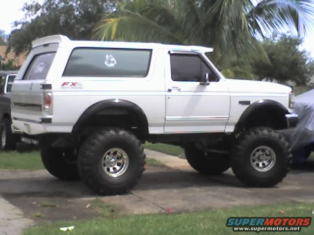 White 1995 Ford Bronco with lifted suspension and large tires, side view
