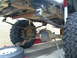 1994 Ford F-250 - Close-up view of the rear axle and suspension system of a truck, showing leaf springs and a large tire.
