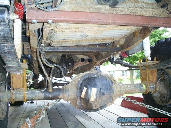 1994 Ford F-250 underside, showing rusty rear axle, leaf springs, fuel tank, and dual exhaust pipes