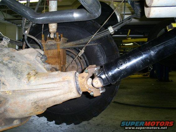 Close-up of a truck's rear axle, leaf springs, shock absorber, and driveshaft