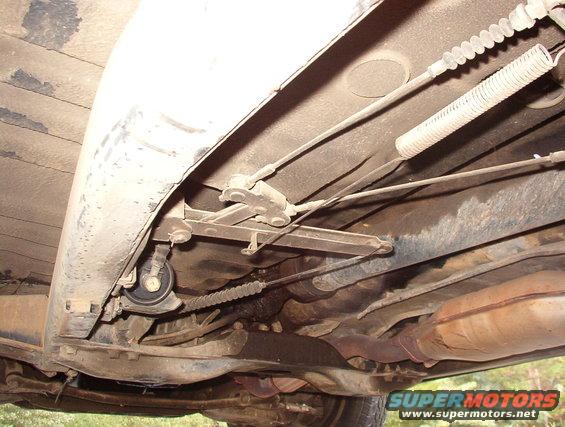 Underside of a vehicle showing suspension cables, exhaust pipe, and catalytic converter