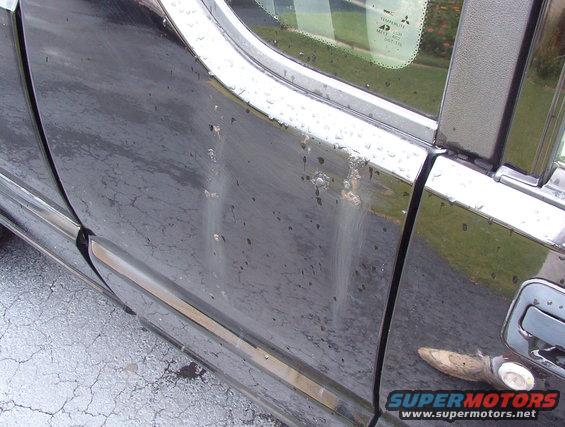 black SUV side door with water spots and a chrome handle