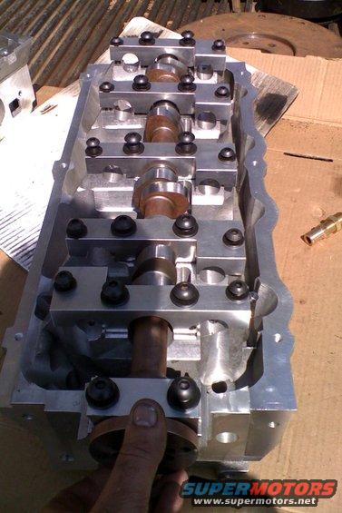 Aluminum engine cylinder head with exposed camshafts and rocker arms, held by a hand