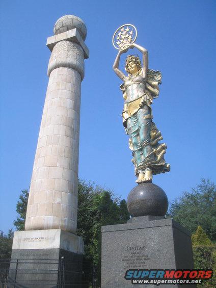 Monument with a globe on top and a statue of a woman holding a star wreath, standing on a sphere
