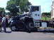 1987 Ford Thunderbird - A black car is severely damaged after being run over by a large white truck.