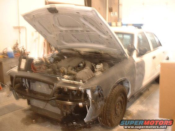 Front of a 2000 Ford Crown Victoria with hood open, showing engine and front end disassembled