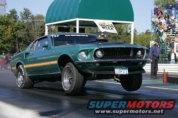 Green 1969 Ford Mustang drag racing, front wheels lifted, gold stripe on side