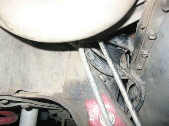 Underside view of engine mounts with wires and hoses, showing rust and dirt