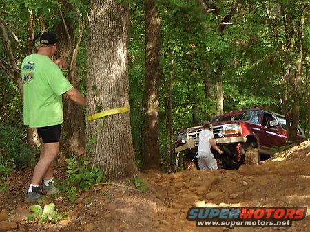 Red SUV with lifted suspension on a muddy trail, front grille visible