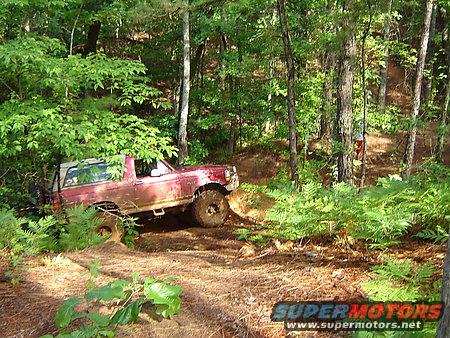 Red 1995 Ford Bronco navigating a wooded trail