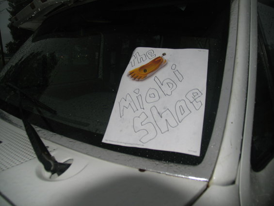 Paper sign with 'the Miobi Shoe' and a foot drawing on a car windshield