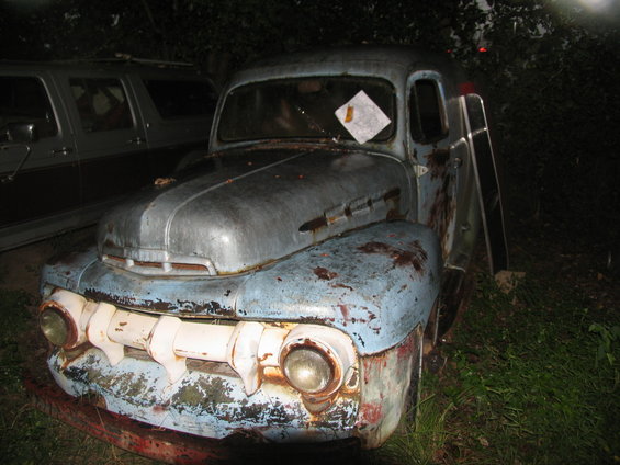 Rusty blue and white truck front, with a paper taped to the windshield